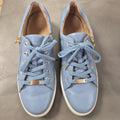 Pair of light blue sneakers with gold accents on a gray surface